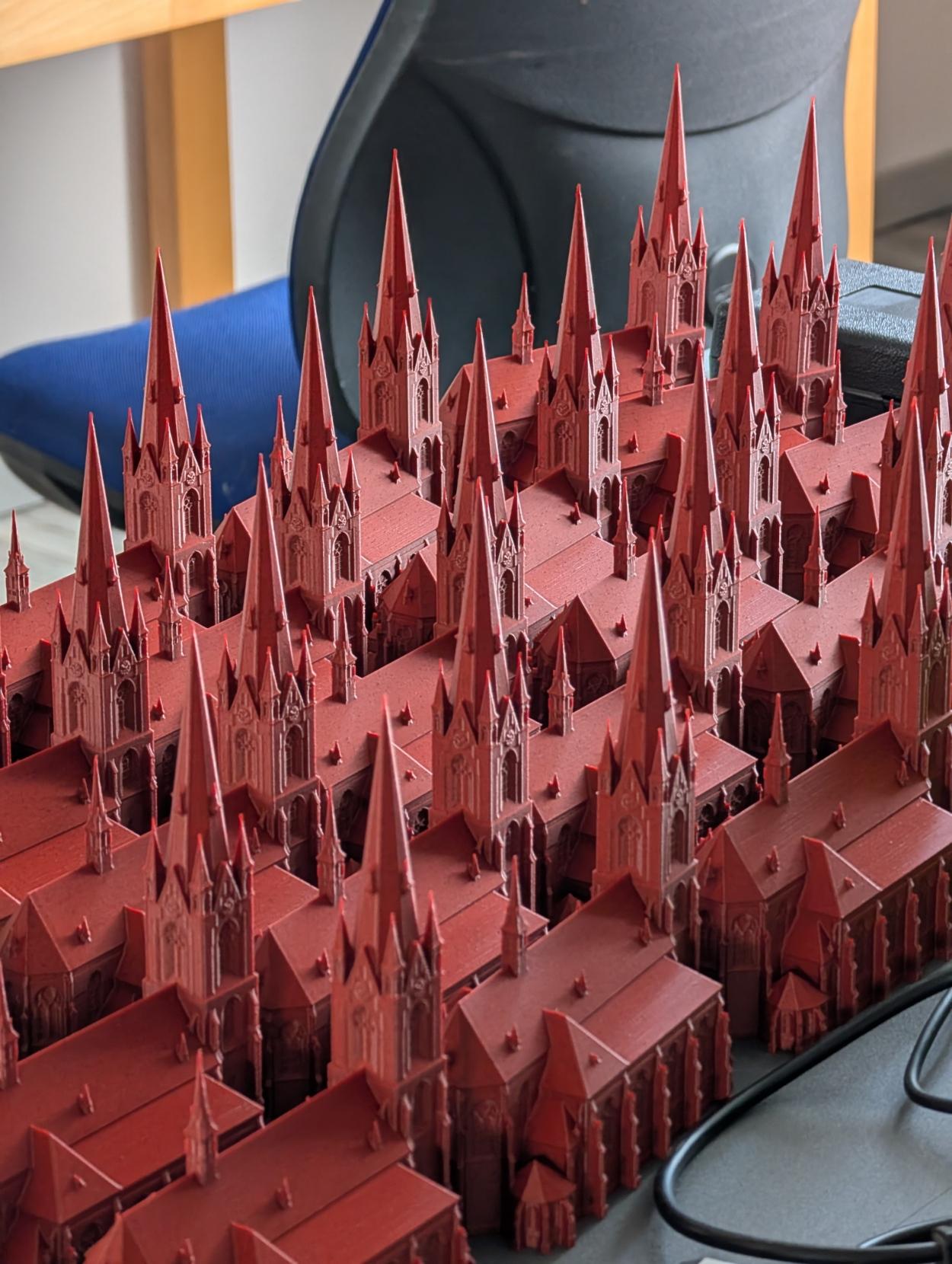 Viele 3D-gedruckte, identische Kirchen-Modelle stehen nebeneinander.